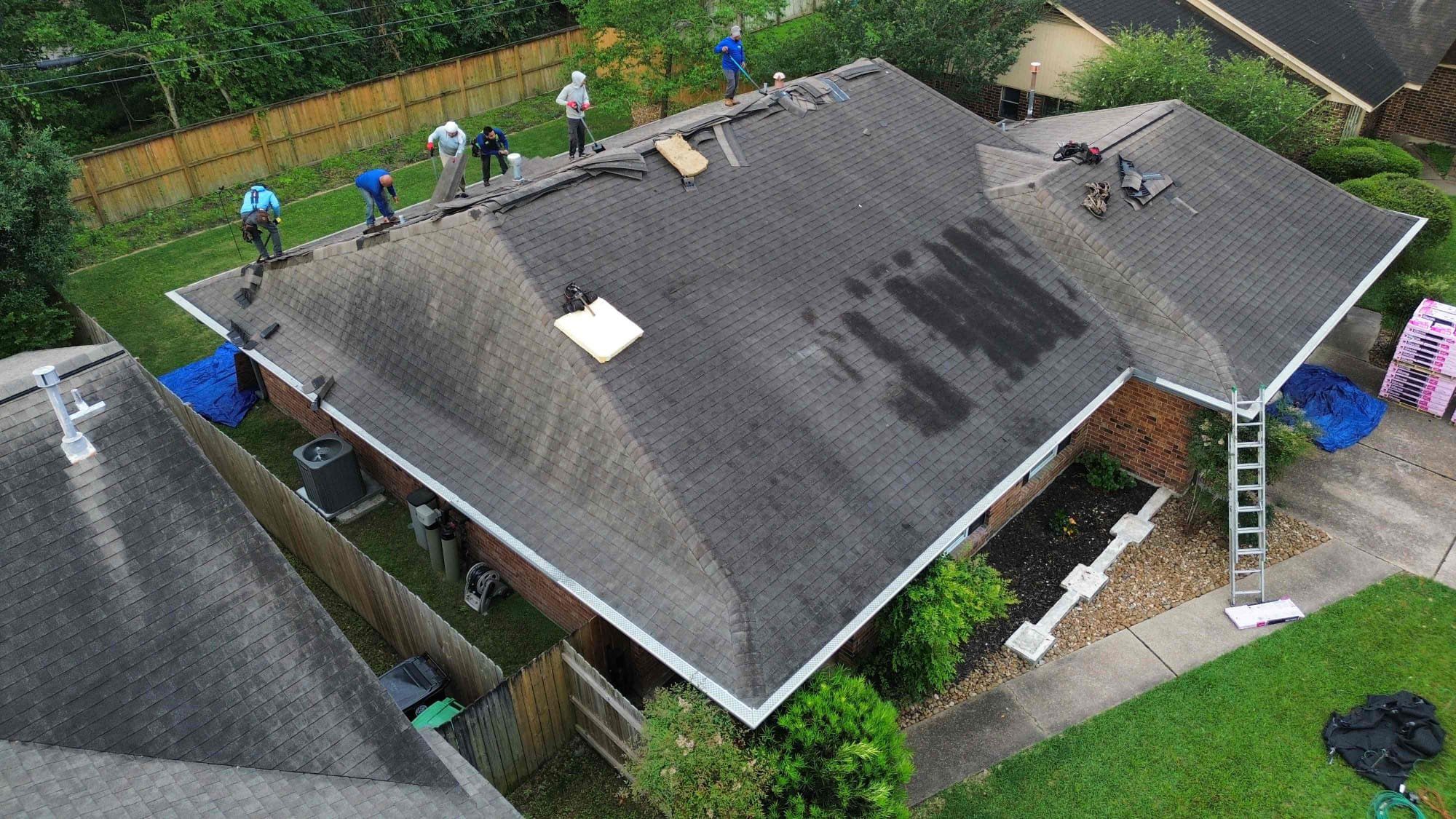 Roofing crew tearing off old shingles before a new roof installation in Humble TX